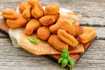 
 Crispy  deep fried     turkey nuggets and ketchup. Breaded  turky efillets  with chilly peppers and fresh basi on wooden rustic background