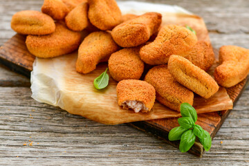 
 Crispy  deep fried     turkey nuggets and ketchup. Breaded  turky efillets  with chilly peppers and fresh basi on wooden rustic background