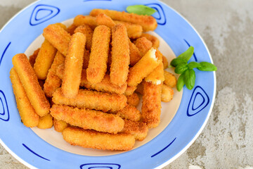 Vegetarian cheese breaded  oven baked  mozzarella sticks with  fresh basil on wooden background 