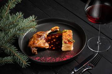 Roasted duck leg confit with cranberry sauce on wooden table.