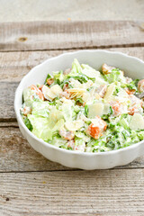 Homemade traditional Caesar Salad with Parmesan Cheese and Croutons in a white bowl on a old white table with leaves and a sauce boat 