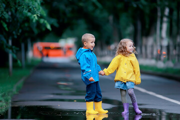 boy and girl children on an autumn walk in the park / autumn park, raincoats for children, family