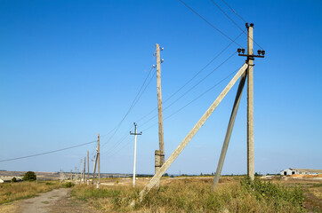 Fototapeta na wymiar Old wooden and new concrete power transmission towers.
