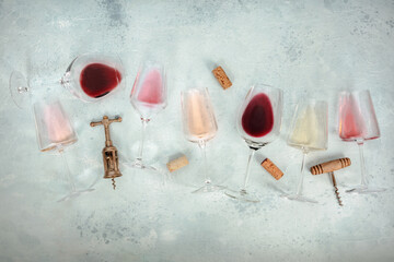 Rose, red, and white wine glasses, with corkscrews and corks, overhead flat lay shot with copy...