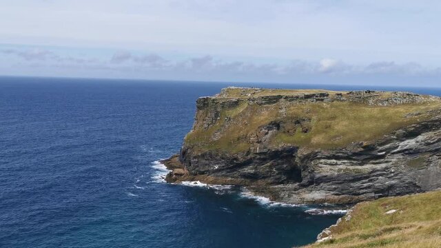 large rock and cliff face in the middle of the coast in the southern most point of england on a cloudless and sunny afternoon at about 12pm
