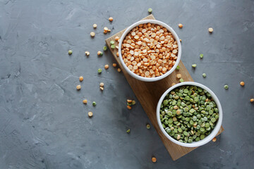 Dry green and yellow peas in bowls, on a gray background. Bean groats.
