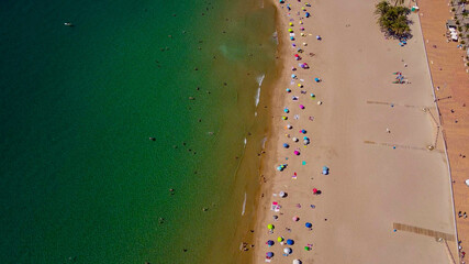 Fototapeta na wymiar Vista cenital de una playa en españa, con las sombrillas y los bañistas en pleno verano