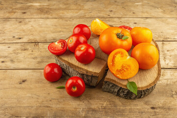 Assorted ripe tomatoes on a wooden stand. Fresh red and orange organic vegetables