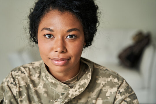 Soldier woman wearing uniform looking at the camera while returning at home