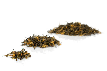 Dry black tea leaves in three groups isolated on white background