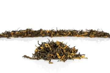 Dry black tea leaves one small group is in the front isolated on white background