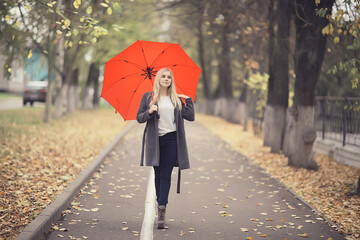 autumn look, sunny day a young girl with an umbrella walks in a yellow park in October