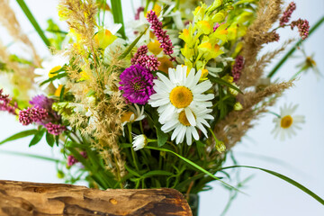 a dry stump, tree bark and a bouquet of wild flowers in a small glass vase. Stylish appearance, layout, personality.