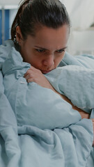 Ill woman with flu using blanket and pillow against shivering at home. Sick adult feeling cold and...