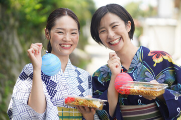 ヨーヨーと焼きそばを持つ女性