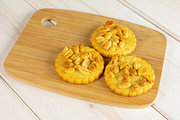 Group of three whole delicious cookie with peanuts on bamboo cutting board on white wood