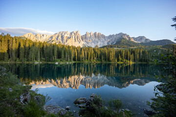 Fototapeta na wymiar Splendid view of Lake Carezza in South Tyrol. The mountains and the forest are perfectly reflected on the lake, a suggestive image. A dream place for a relaxing holiday in nature.