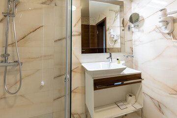 Interior of a luxury bathroom with marble walls and shower cabin