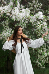 Portrait of a woman in the branches of a blooming apple tree. Beautiful natural makeup