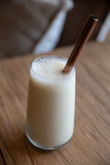 healthy breakfast. banana smoothie in glass and straw on a wooden background