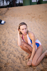 Young white woman in swimsuit sitting on the beach