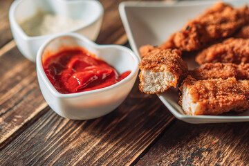 Chicken nuggets on plate next to cup of sauce