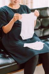 新生児用の肌着を持つ妊婦