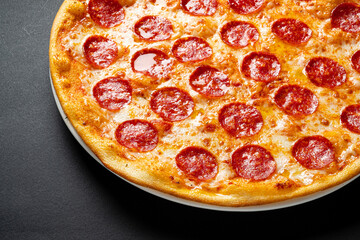 Tasty pepperoni and tomatoes on black background