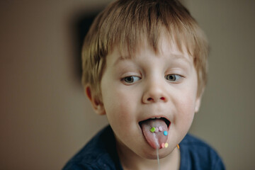 close up portrait of cute caucasian boy having a sugar topping on his tongue stuck out. image with selective focus - obrazy, fototapety, plakaty