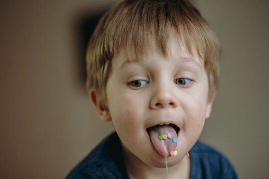 close up portrait of cute caucasian boy having a sugar topping on his tongue stuck out. image with selective focus