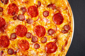 Tasty pepperoni and tomatoes on black background