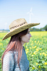 Obraz premium White girl with dark hair in straw hat with sky behind in meadow