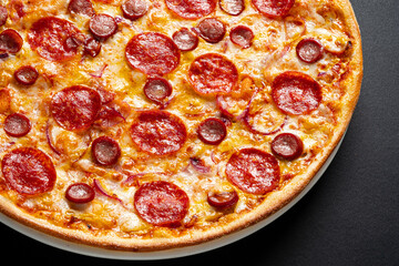 Tasty pepperoni and tomatoes on black background