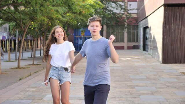 Guy is walking and young lady is going behind him