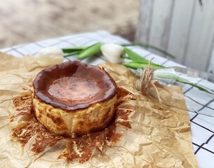 Cheesecake on crumpled paper  and white flowers on the table
