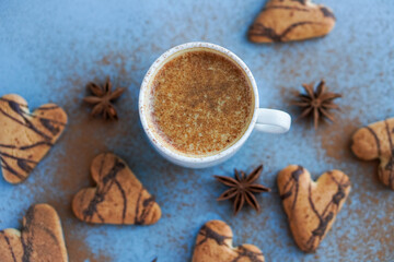 Flatlay of cup of coffee spiced with cinnamon near brown cookies and star anise