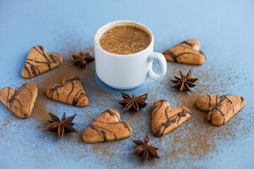 Obraz na płótnie Canvas White cup of coffee spiced with cinnamon near brown cookies and star anise