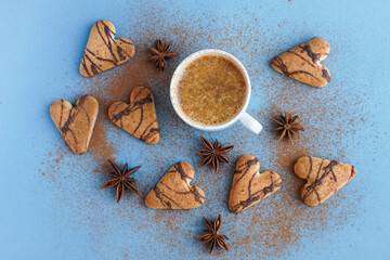 Flatlay of cup of coffee spiced with cinnamon near brown cookies and star anise