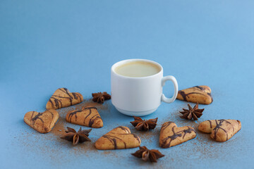 White cup of coffee near brown cookies and star anise spiced with cinnamon
