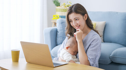 パソコンで仕事をするママと赤ちゃん（家族・ファミリー・育児・子育て・ビジネス）