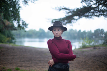 White european woman in black hat with lake behind