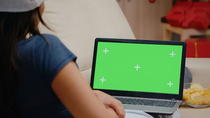 Naklejka premium Close up of person watching horizontal green screen on laptop. Woman looking at chroma key on modern device with isolated background and mockup template. Adult with gadget screen