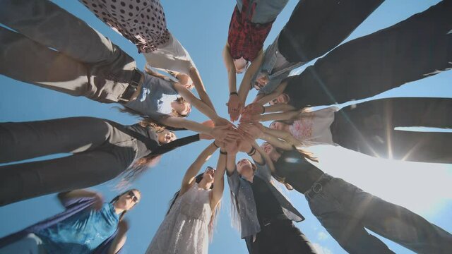 Eleven cheerful girlfriends make their hands together on a sunny day.