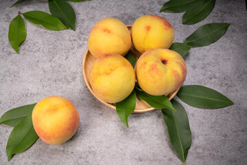 Golden Yellow Peach in wooden plate on gray background.