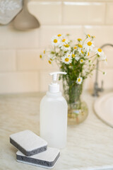 Fototapeta na wymiar Eco friendly non-toxic cleaning dish soap with chamomile flowers, clean white plates