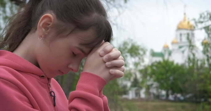 Child pray for God by the church. A young teen pray for God by the chutch.