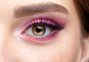 Fototapeta premium Closeup macro shot of human female eye with pink eyes shadows