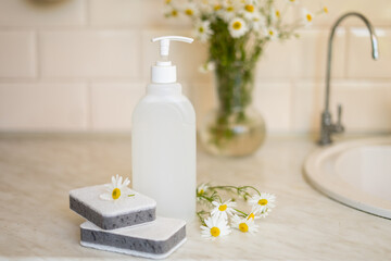 Fototapeta na wymiar Eco friendly non-toxic cleaning dish soap with chamomile flowers, clean white plates