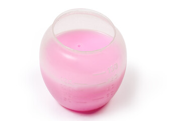 Liquid laundry detergent in measuring cup on a white background