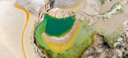 Colored lake among rock dumps of abandoned quarry, aerial view